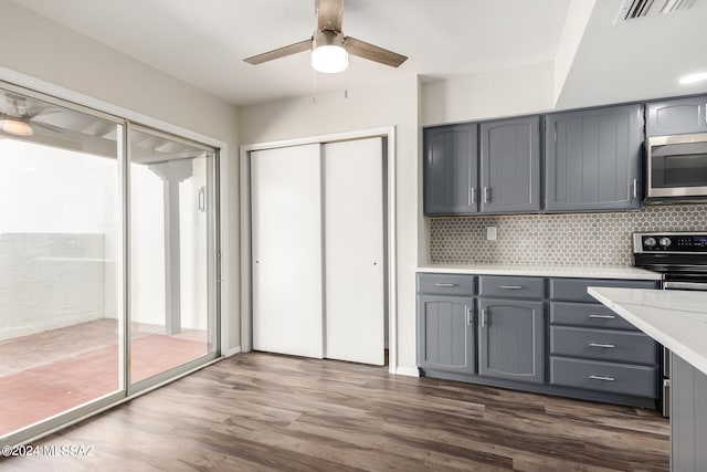 kitchen with gray cabinetry, ceiling fan, stainless steel appliances, and dark hardwood / wood-style floors