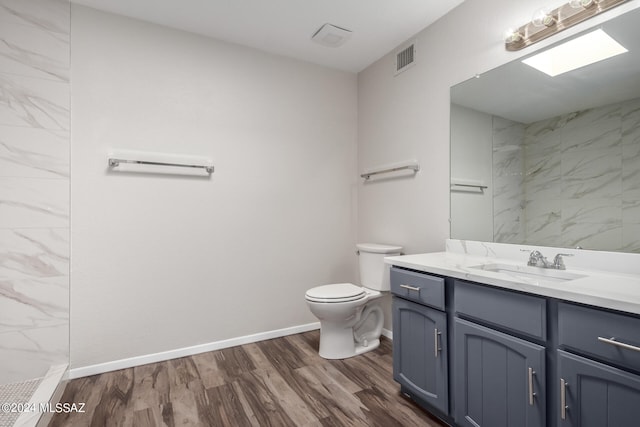 bathroom featuring tiled shower, vanity, toilet, and hardwood / wood-style flooring