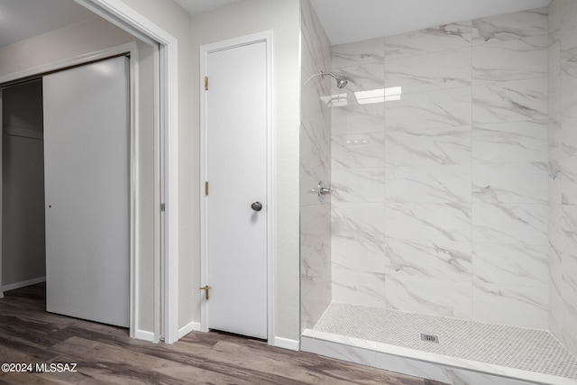 bathroom with tiled shower and wood-type flooring