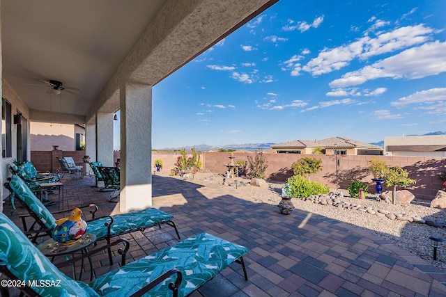 view of patio with ceiling fan and a mountain view