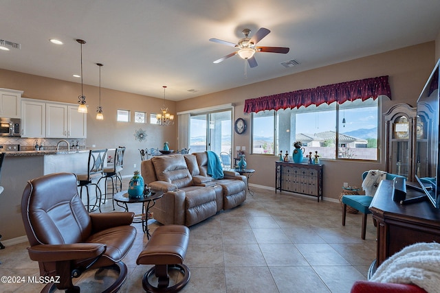 living room with ceiling fan with notable chandelier, a wealth of natural light, and light tile patterned flooring