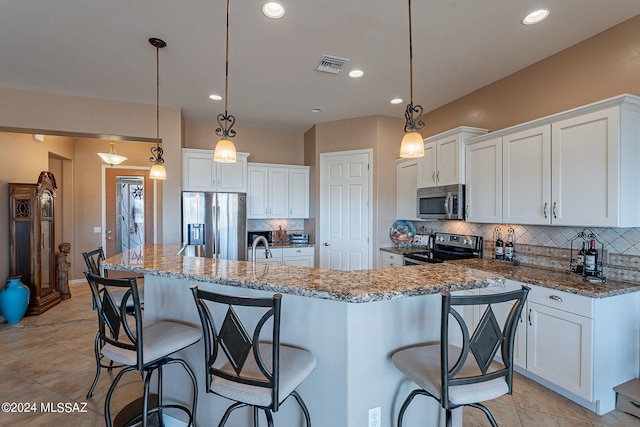 kitchen featuring stainless steel appliances, white cabinets, dark stone countertops, and hanging light fixtures