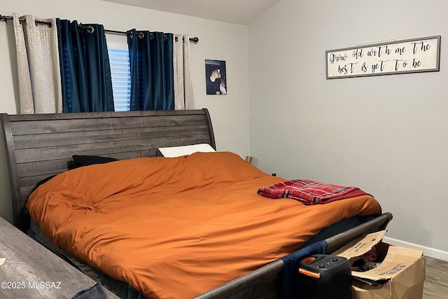 bedroom with lofted ceiling, wood finished floors, and baseboards