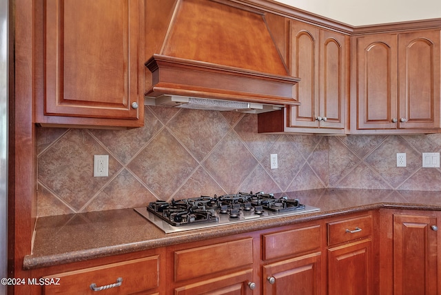 kitchen featuring stainless steel gas stovetop, custom exhaust hood, and backsplash