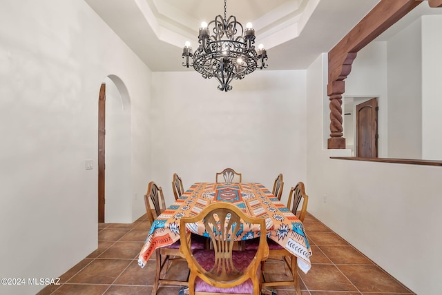 dining area featuring a notable chandelier, dark tile patterned floors, and a tray ceiling