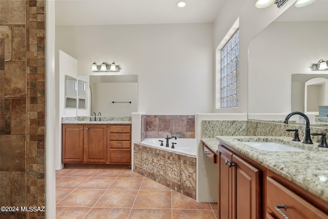 bathroom featuring tile patterned flooring, vanity, and tiled tub