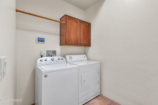 laundry area with cabinets, washing machine and dryer, and light tile patterned flooring