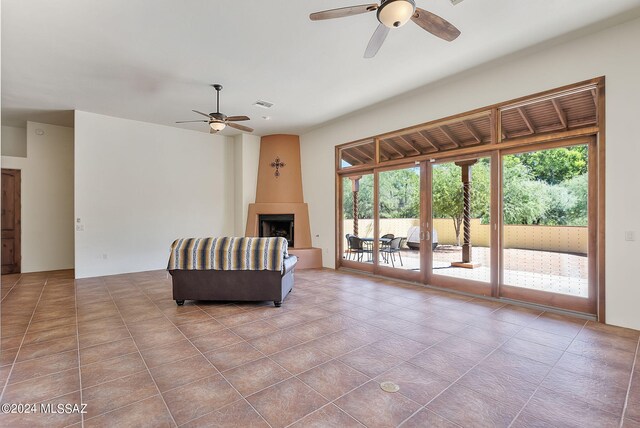 living area featuring a large fireplace, ceiling fan, light tile patterned floors, and french doors