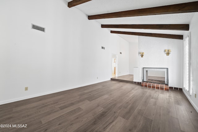 unfurnished living room featuring vaulted ceiling with beams, dark hardwood / wood-style floors, and a tiled fireplace