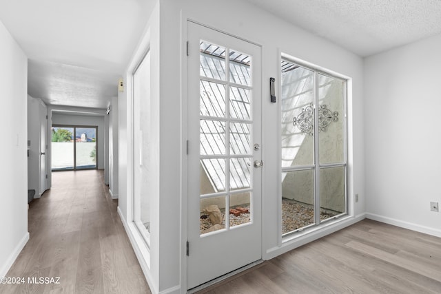 doorway to outside featuring a textured ceiling and light wood-type flooring