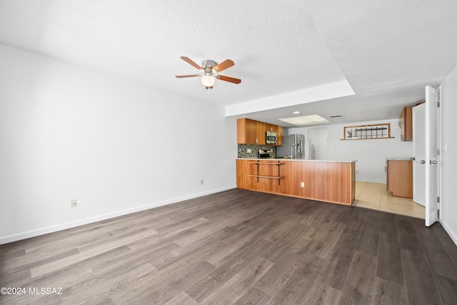 unfurnished living room with ceiling fan, light hardwood / wood-style flooring, and a textured ceiling