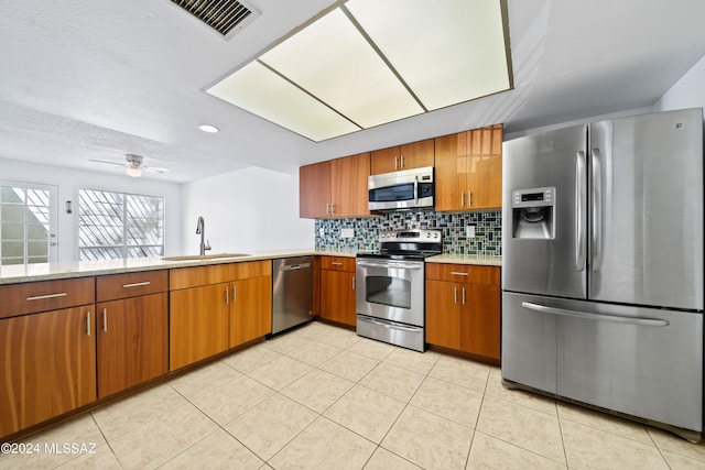 kitchen with tasteful backsplash, stainless steel appliances, ceiling fan, sink, and light tile patterned flooring