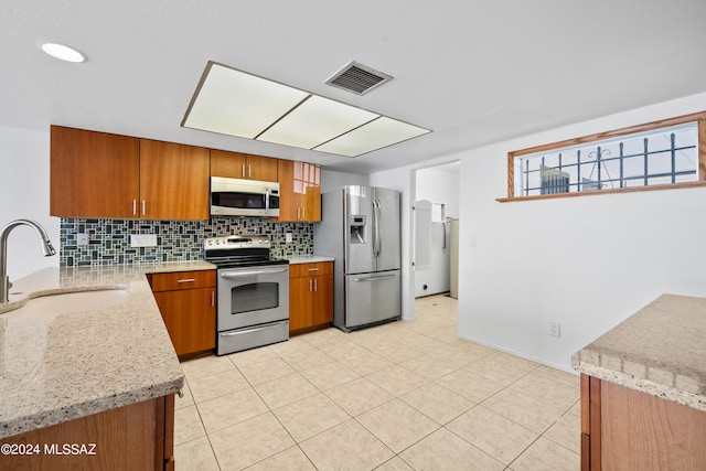 kitchen with light stone countertops, appliances with stainless steel finishes, tasteful backsplash, sink, and light tile patterned floors