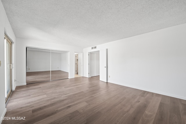 unfurnished bedroom featuring hardwood / wood-style floors, a textured ceiling, and a closet