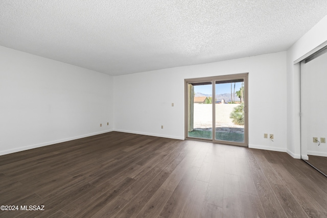 spare room featuring a textured ceiling and dark wood-type flooring