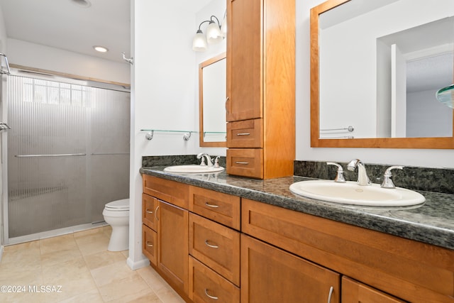 bathroom featuring tile patterned flooring, vanity, toilet, and an enclosed shower