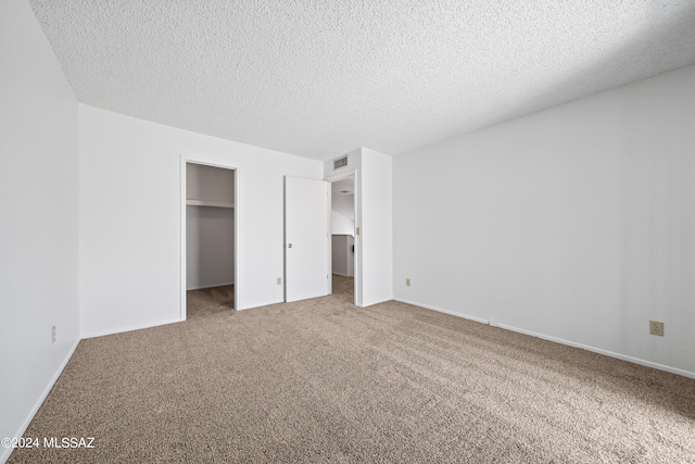 unfurnished bedroom with a textured ceiling, carpet floors, and a closet