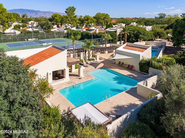 view of pool featuring a multi sided fireplace, a mountain view, and tennis court