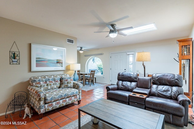 tiled living room with visible vents, a ceiling fan, baseboards, and a skylight