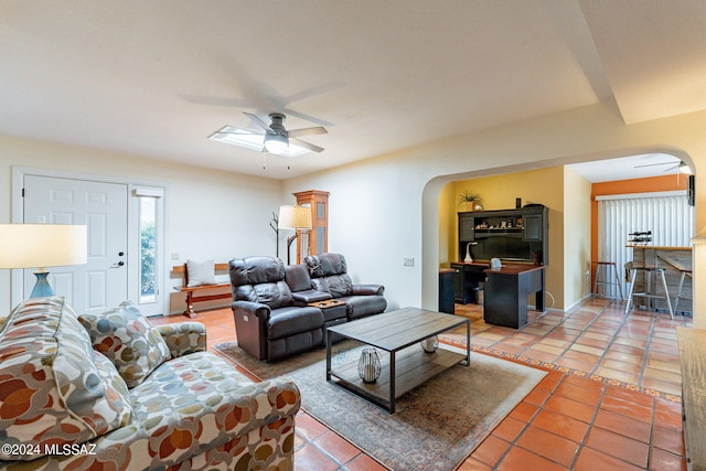 living room with a ceiling fan, arched walkways, and light tile patterned floors
