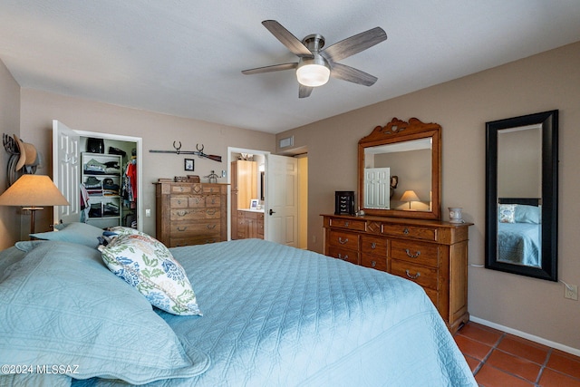 tiled bedroom featuring a walk in closet, ceiling fan, visible vents, baseboards, and connected bathroom