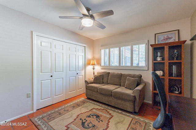 living area with light tile patterned floors, baseboards, and a ceiling fan