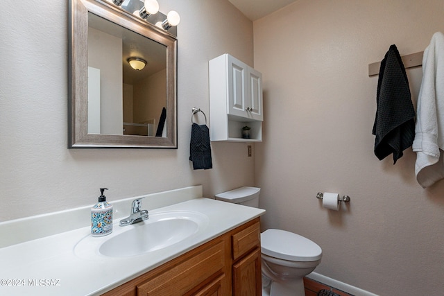 bathroom with toilet, baseboards, and vanity