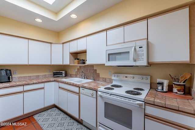 kitchen with a toaster, white appliances, recessed lighting, white cabinets, and a sink
