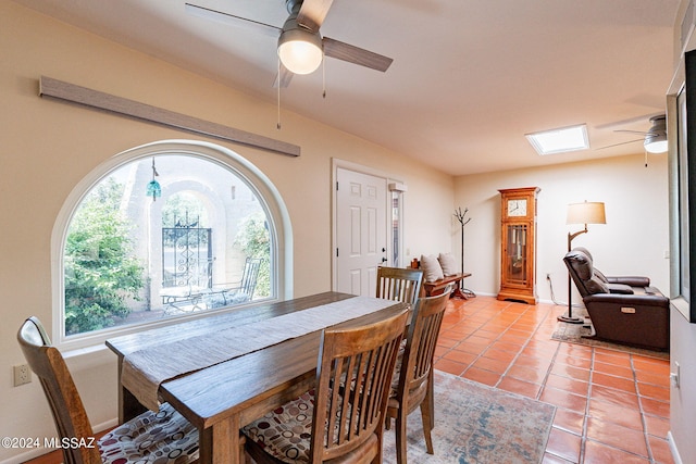 tiled dining room featuring ceiling fan and a skylight