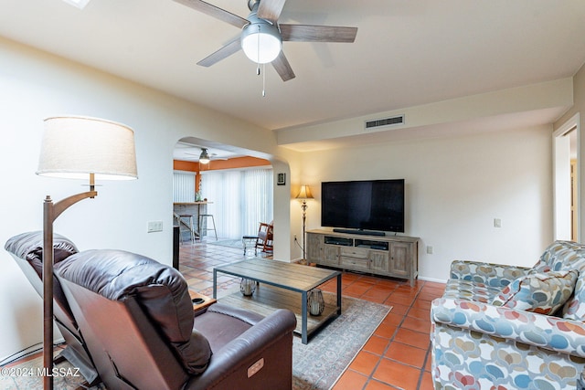 tiled living room with visible vents, arched walkways, and ceiling fan