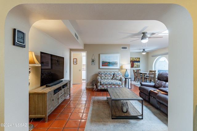 tiled living area featuring visible vents, arched walkways, and ceiling fan
