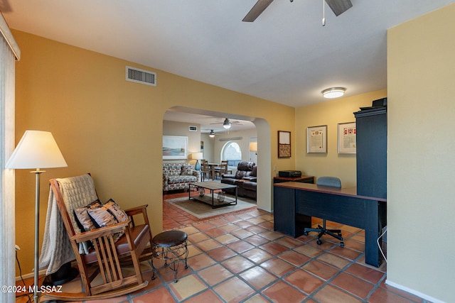 tiled home office featuring visible vents, a ceiling fan, and arched walkways