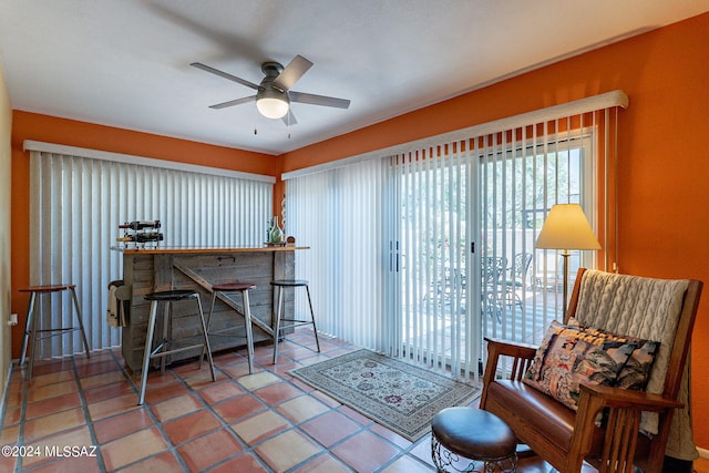 sitting room featuring tile patterned flooring, bar area, and ceiling fan