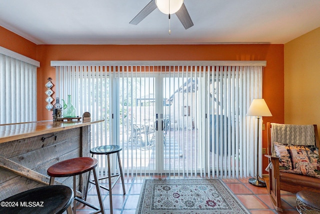 interior space featuring bar, light tile patterned floors, and ceiling fan