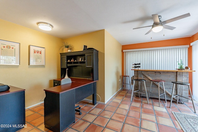 office space with baseboards, a dry bar, and ceiling fan