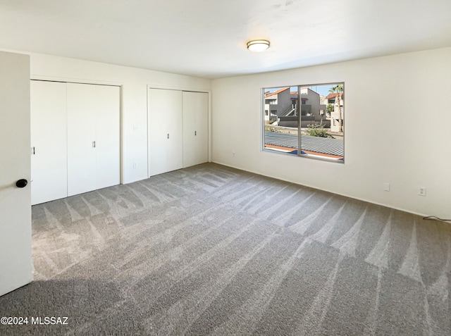 unfurnished bedroom featuring multiple closets and carpet flooring