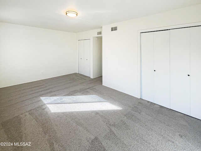 unfurnished bedroom with carpet and two closets