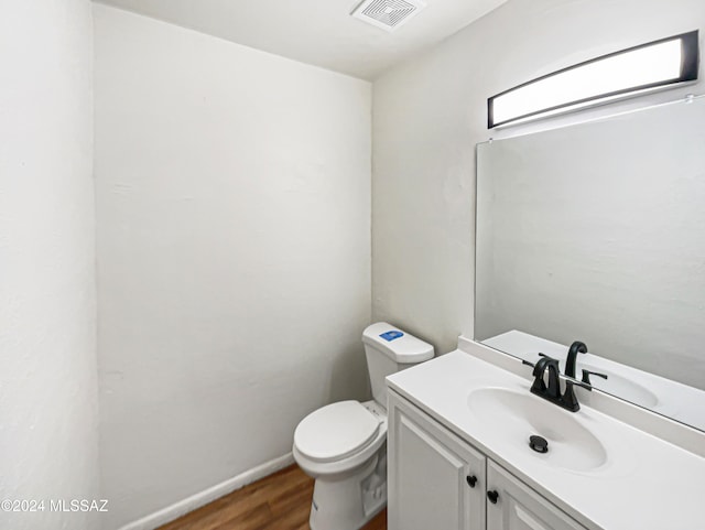 bathroom with vanity, toilet, and hardwood / wood-style floors