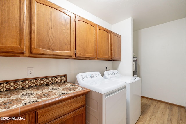 washroom with cabinets, light wood-type flooring, and washing machine and clothes dryer