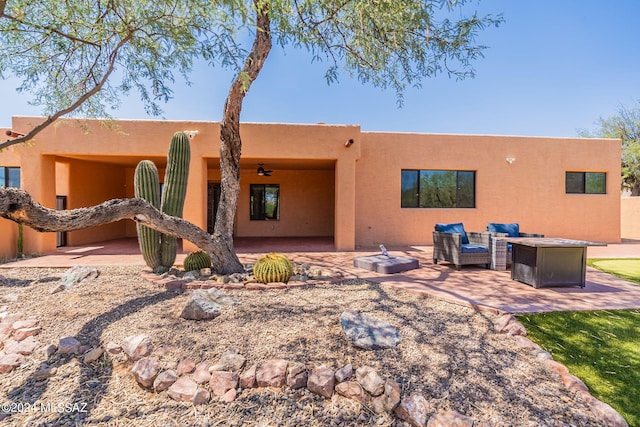 rear view of house featuring ceiling fan, an outdoor living space with a fire pit, and a patio