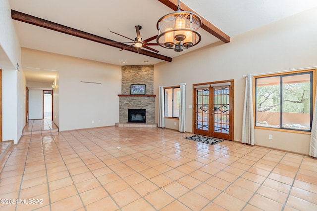 unfurnished living room with ceiling fan with notable chandelier, french doors, light tile patterned floors, and beamed ceiling