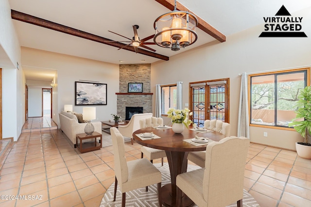 dining area with a fireplace, beam ceiling, light tile patterned flooring, french doors, and ceiling fan with notable chandelier