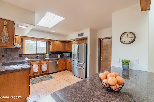 kitchen featuring tasteful backsplash, a skylight, appliances with stainless steel finishes, and sink