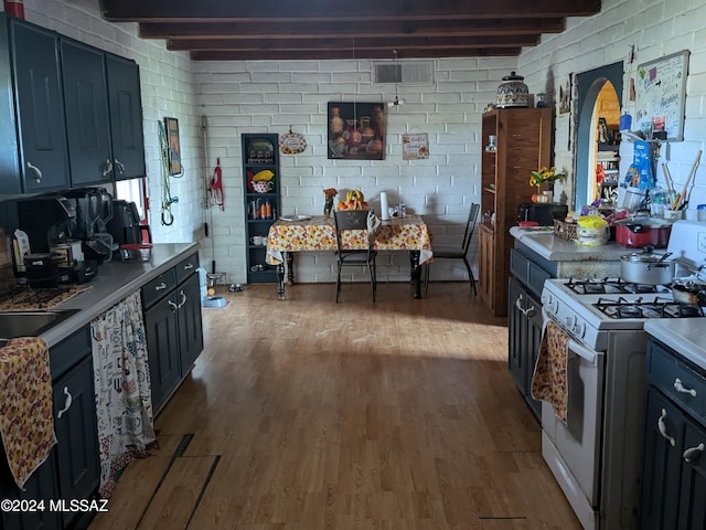 kitchen with white range with gas stovetop, light hardwood / wood-style floors, and beam ceiling