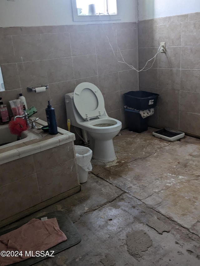 bathroom with a tub, tile walls, and toilet