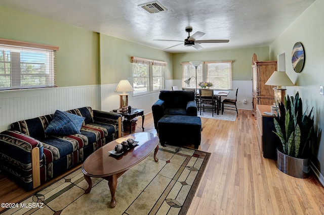 living room with a textured ceiling, light hardwood / wood-style flooring, and ceiling fan