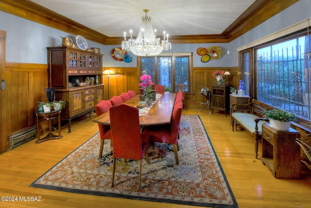 dining area with ornamental molding, a baseboard heating unit, a notable chandelier, and light hardwood / wood-style floors