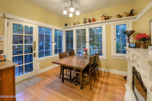 dining area with a high end fireplace, light hardwood / wood-style flooring, and an inviting chandelier