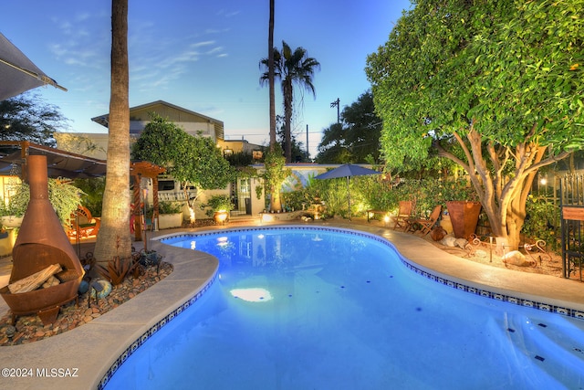 pool at dusk featuring a patio area