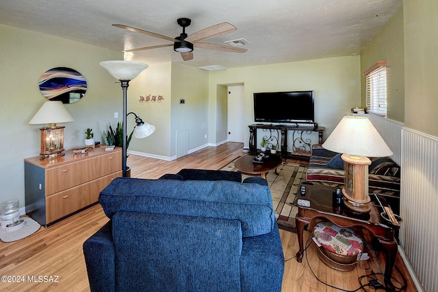 living room with ceiling fan, a textured ceiling, and light hardwood / wood-style flooring